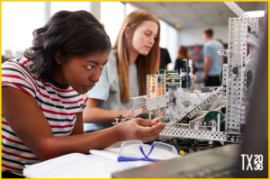 Two young girls tinker with robotics in a classroom with the help of a virtual teacher. 