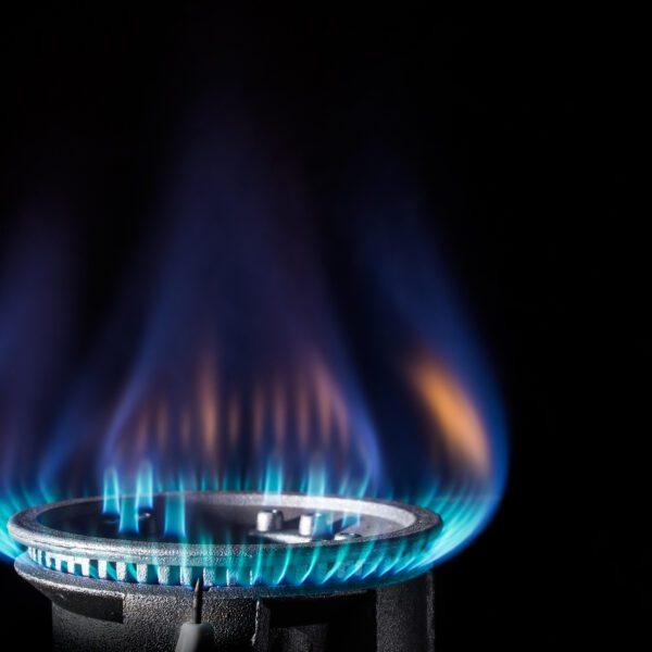 A gas range is lit against a black backdrop. The flame is a mix of blues and oranges.