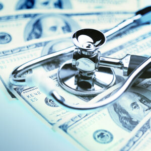 A doctor's stethoscope is laid on top of hundred dollar bills. It figuratively represents healthy and unhealthy markets.