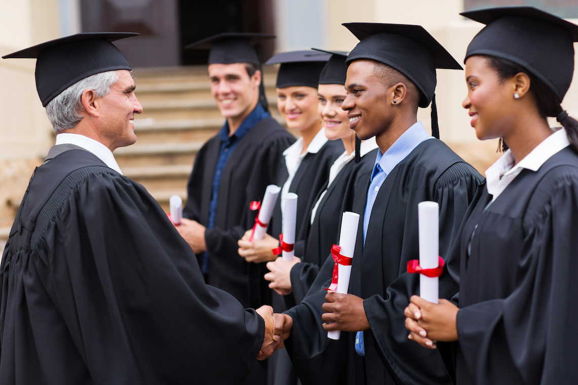 College administrator congratulating new graduates as they receive their diplomas